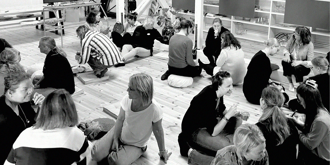Teachers and municipal staff sitting on the floor in small groups, working together.