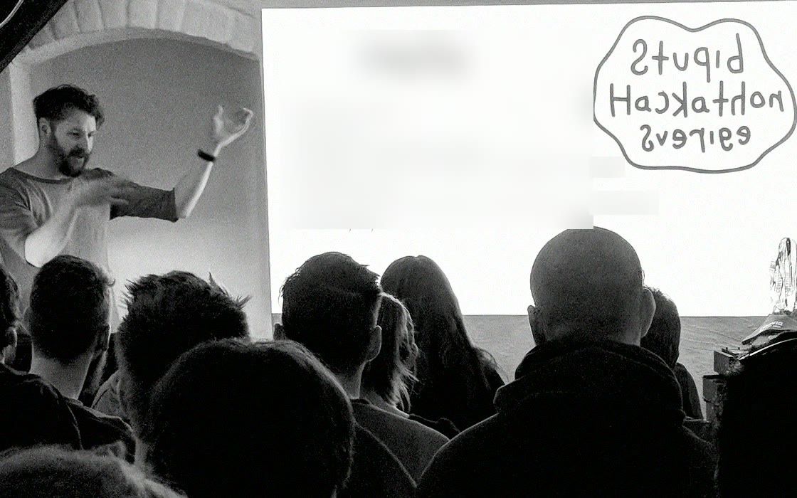 Stupid Hackathon: the host welcomes a full room in front of the day’s schedule