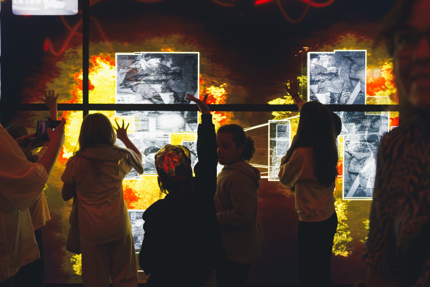 Visitors in front of the documentary, their movement glowing as energy around the archive film