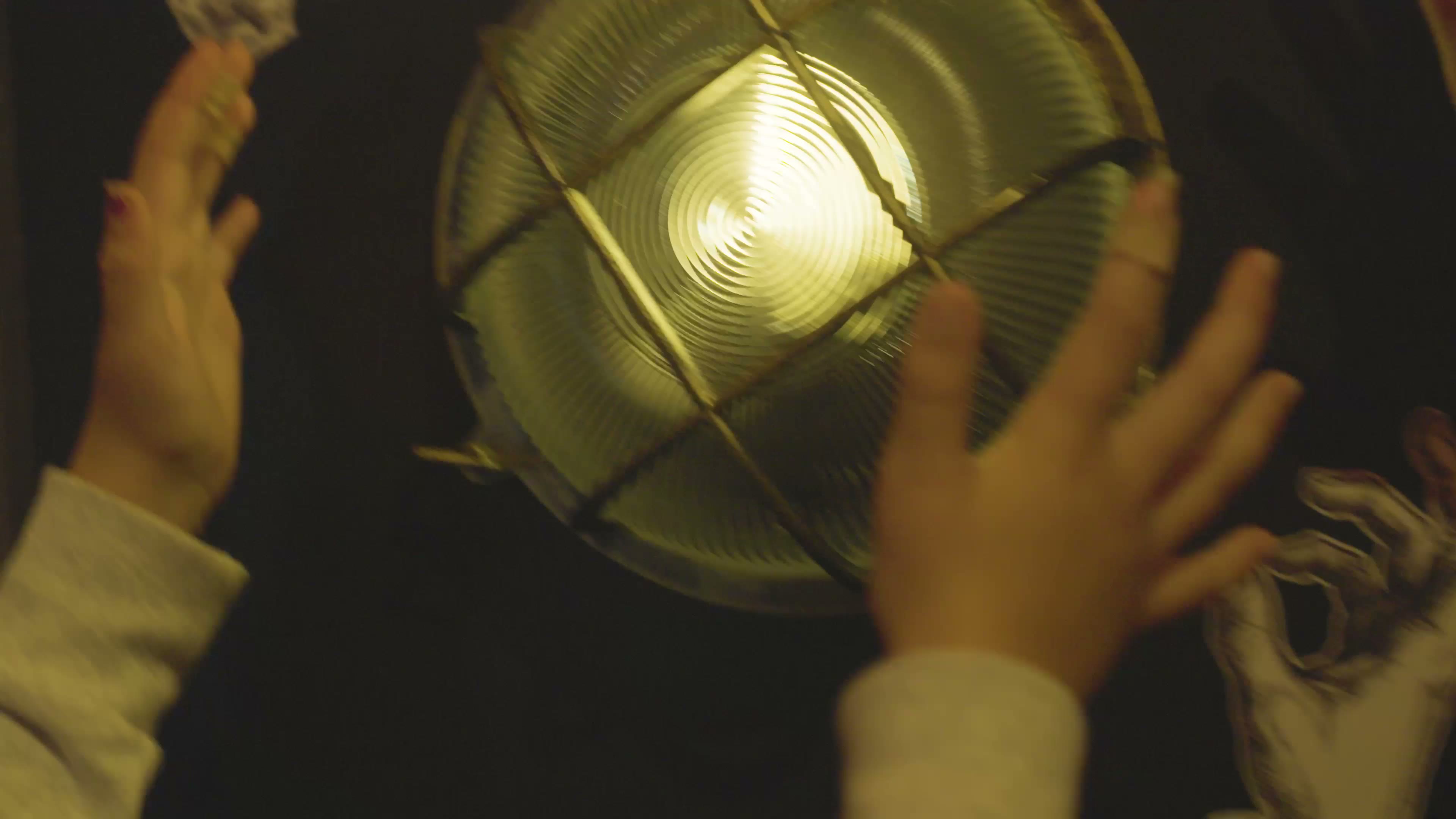Hands around a caged incandescent lamp