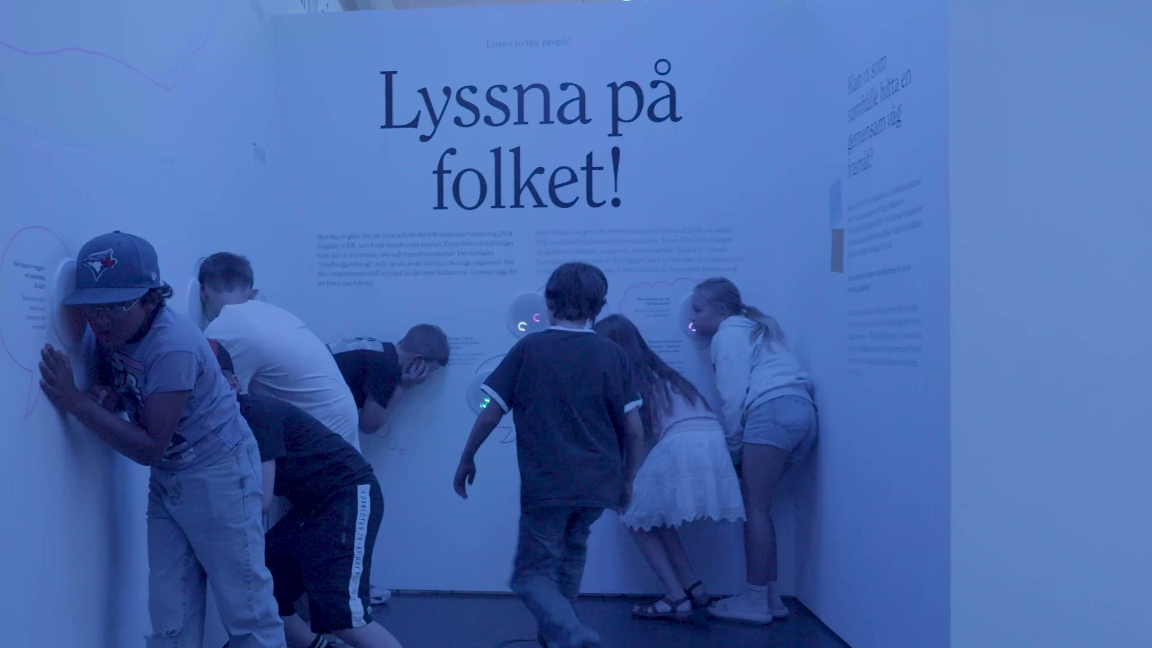 Children with their ears to a wall under the words Lyssna på folket!
