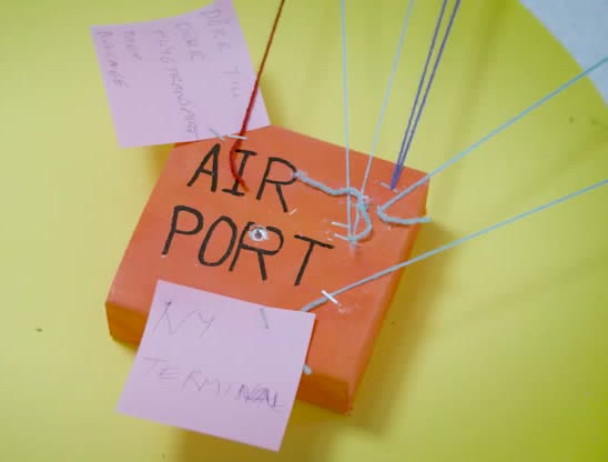 An orange block marked Airport, tied with yarn